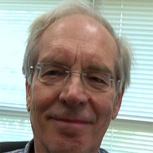 Bill smiling face with glasses in front of his office blinds